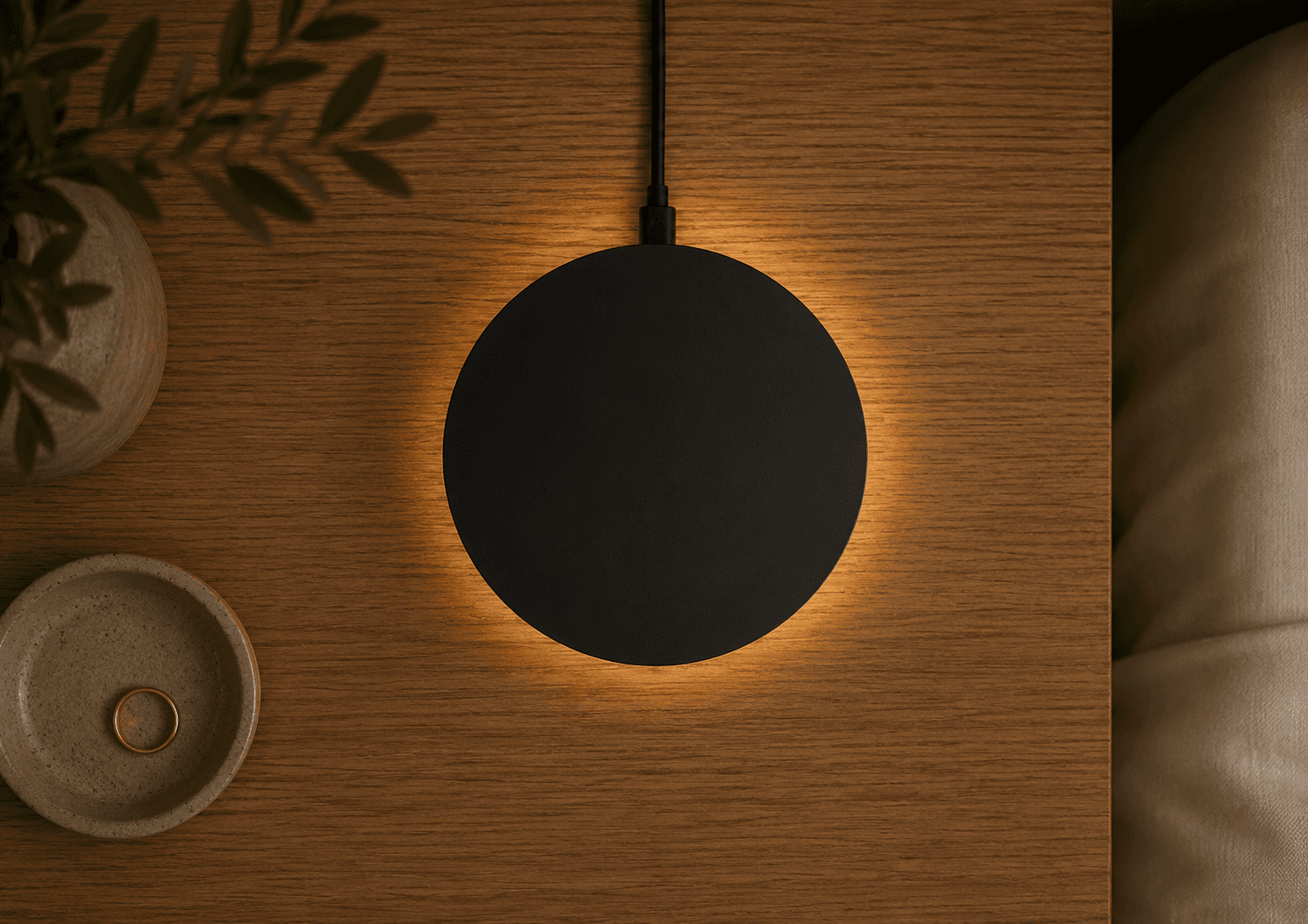 The Dormio sensor on a wooden nightstand, lit from beneath by a warm glow