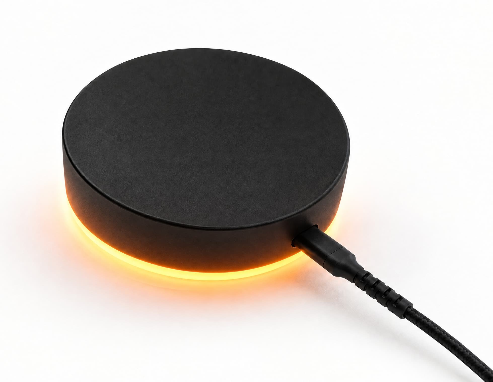 The Dormio sensor, a matte black disc lit from beneath by a warm amber glow, with a braided cable running from its side